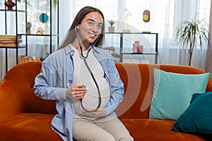 Happy pregnant young woman using stethoscope listening to baby heartbeat unborn child vital signs