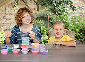 happy preschool boy sits at a table with his older sister or nanny, busy with creative game