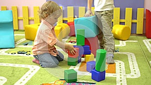 Happy preschool children playing with multi coloured blocks at indoor playground.
