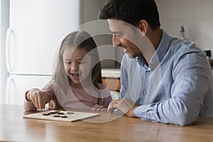 Happy preschool daughter kid and handsome dad playing board game