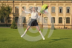 happy preschool girl with backpack. jumping in school yard. back to school. child in uniform celebrate end of year