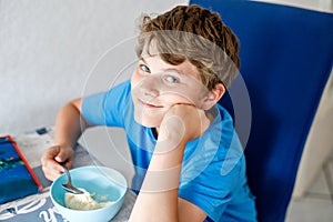 Happy preteen blond kid boy eating cereals for breakfast or lunch. Healthy eating for children in the morning. School