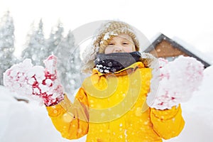 Happy preteen boy having fun playing with fresh snow during vacation in european Alps. Child dressed in warm clothes, hat, hand