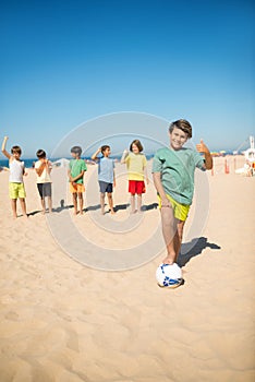 Happy preteen boy playing football with friends