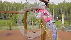 Happy preteen girl having fun on swing on playground