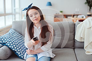 happy preteen girl watching tv and relaxing at home on cozy couch