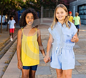 Happy preteen girls walking along city street