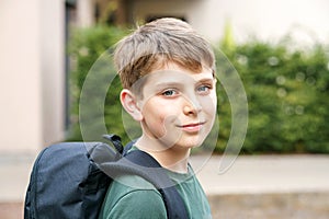 Happy preteen kid boy with backpack or satchel. Schoolkid in on the way to elementary or middle school on warm sunny