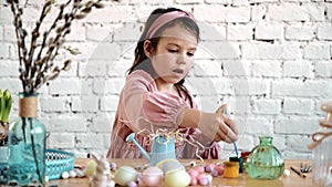Happy pretty child girl having fun during painting eggs for Easter in spring time at home. Child painting eggs. Happy