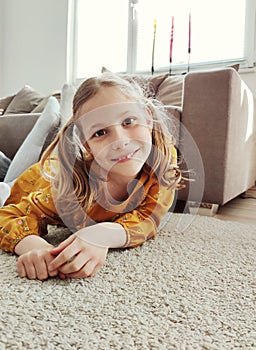 Happy pretty child girl in yellow dress on sofa at home