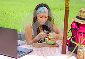 Happy and pretty digital nomad Asian Chinese girl taking picture of fruit salad with mobile phone for sharing on internet social m