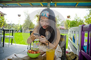 Happy and pretty digital nomad Asian Korean girl taking picture of fruit salad with mobile phone for sharing on internet social me