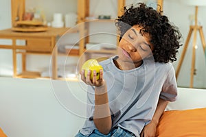 Happy pretty girl biting green apple at home. Beautiful african american young woman eating fresh fruit and smiling