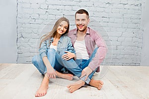 Happy pretty man and woman sitting barefoot on the floor