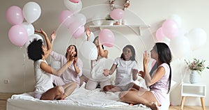 Happy pretty mixed race female friends having fun in bedroom.