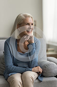 Happy pretty old mature woman relaxing on home couch