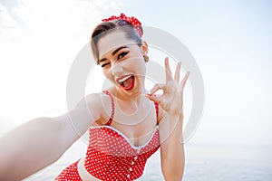 Happy pretty pinup girl in red swimsuit showing okay sign