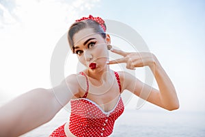 Happy pretty pinup girl in red swimsuit showing victory sign