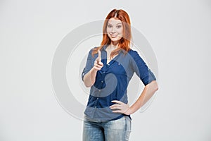 Happy pretty redhead young woman standing and pointing on you
