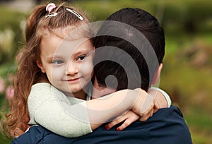 Happy pretty smiling kid girl hugging her father with love outdo