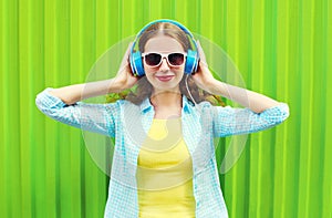 Happy pretty smiling woman listens to music in headphones over green