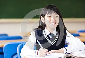 Happy pretty student girl with books in classroom