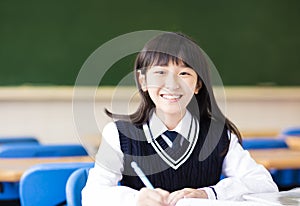 Happy pretty student girl with books in classroom