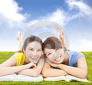 Happy pretty students lying on the grassland with books