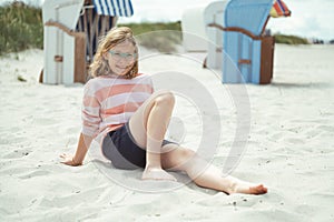 Happy pretty teen girl sitting on sunny white beach at summer holidays