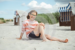 Happy pretty teen girl sitting on sunny white beach at summer holidays