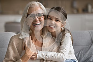 Happy pretty tween granddaughter girl hugging loving grandma from behind