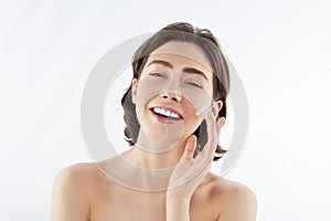 Happy pretty woman applying cream on face