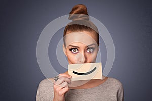 Happy pretty woman holding card with funny smiley