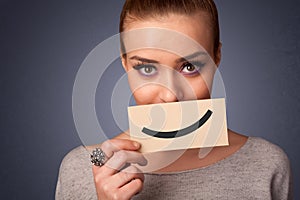 Happy pretty woman holding card with funny smiley