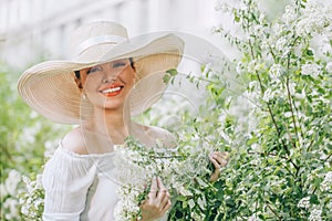 Happy pretty woman wearing white hat with flowers outdoors portrait