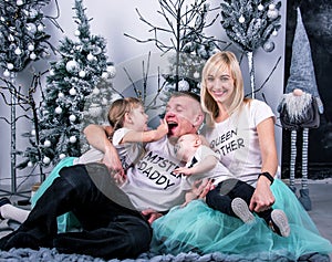 Happy pretty young couple having fun on the background of Christmas decor with children with smiles on New Year`s Eve