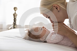 Happy pretty young mom cuddling sweet baby lying on back