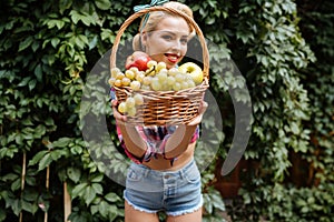 Happy pretty young woman giving you basket of fresh fruits