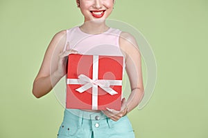 Happy pretty young woman holding gift box over green background