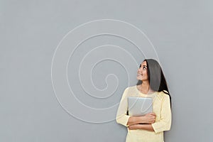 Happy pretty young woman holding laptop and looking away