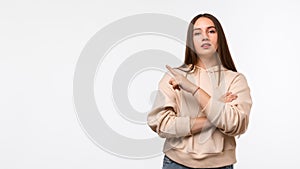 Happy Pretty young woman with long chestnut hair, pointing finger to the side, shows copy space for your information