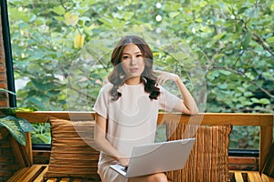 Happy pretty young woman sitting on sofa and using laptop at home