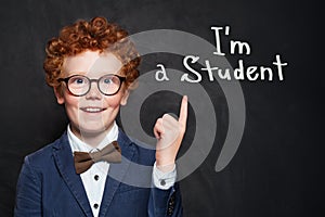 Happy prodigy child student on blackboard background portrait