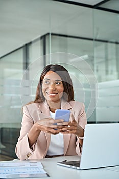 Happy professional African American business woman using phone in office.