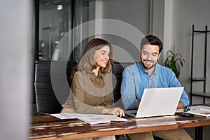 Happy professional business people working in office with laptop and talking.