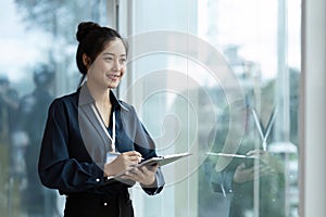 happy professional business woman working with paperwork at work standing near window