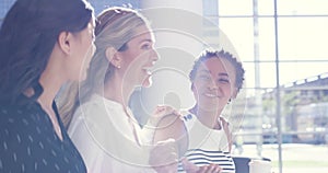 Happy professional businesswomen on coffee break together. Diverse female friend group laughing, talking and smiling