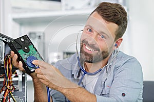 Happy professional repairman repairing computer in workshop