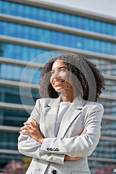 Happy proud young African American business woman standing in city, vertical.