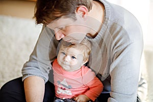 Happy proud young father having fun with baby daughter, family portrait together. Dad with baby girl, love. Man playing